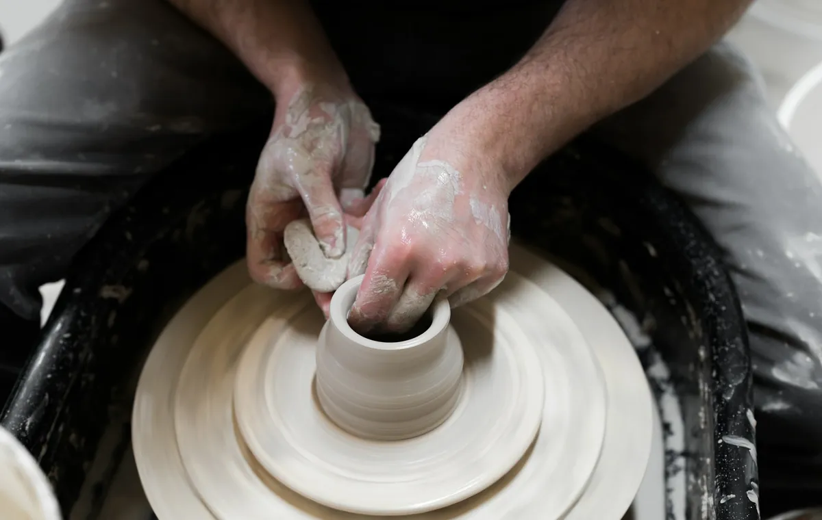 Mains façonnant un pot sur un tour de potier pendant un atelier