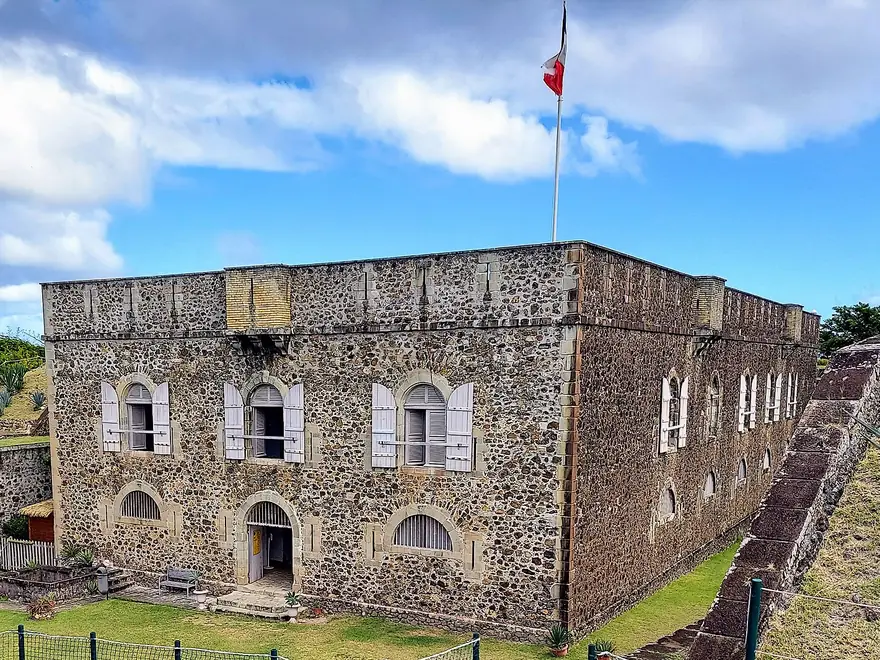 Le Fort Napoléon des Saintes, à Terre-de-Haut : bâtiment en pierre aux volets clairs, drapeau tricolore sur le toit