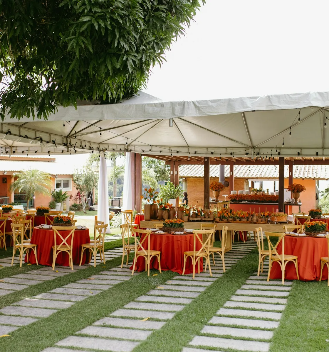 Tables dressées sous un chapiteau blanc dans un jardin tropical, avant l'arrivée des invités